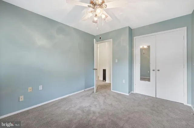 a view of an empty room and chandelier fan