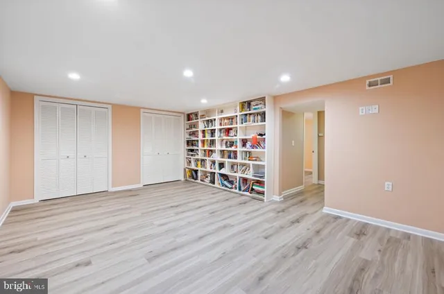 a view of an empty room with wooden floor and closet
