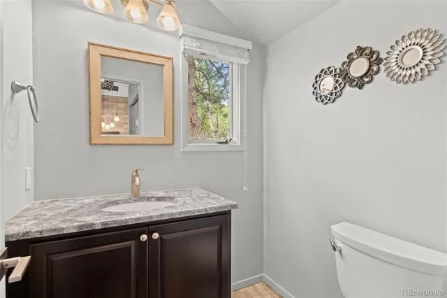 a bathroom with a granite countertop sink a toilet and mirror