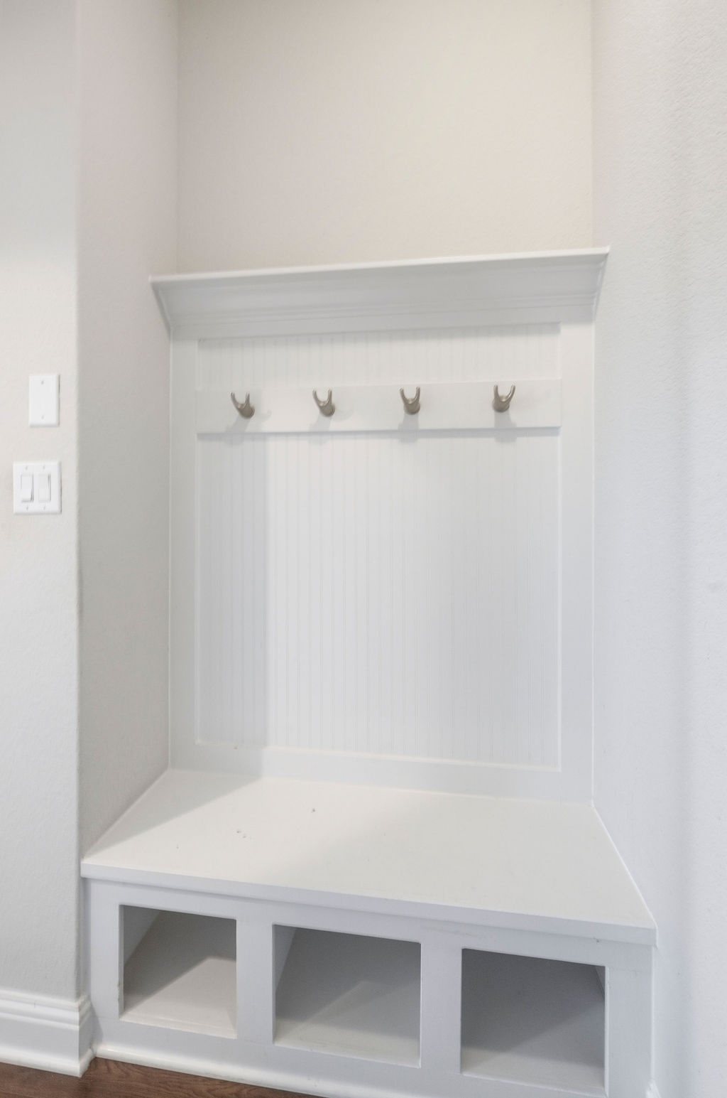 2032 Base Burner Path Leander, TX 78641 - Photo 30 of 34 Built-in white mudroom bench featuring beadboard paneling, four storage cubbies, four brass-finish coat hooks, and a decorative top shelf