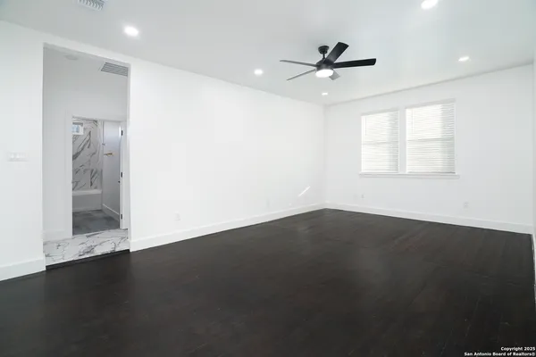 an empty room with wooden floor and windows