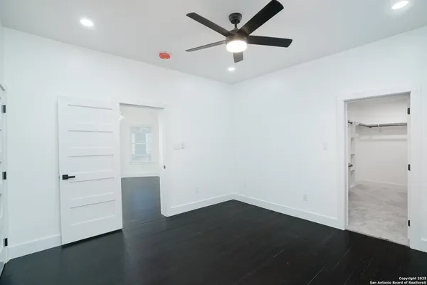 an empty room with wooden floor and ceiling fan