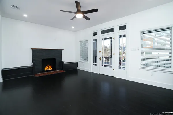 a view of an empty room with wooden floor fireplace and a window