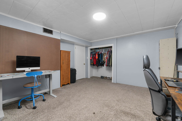 9902 South Poppy Lane Sandy, UT 84094 - Photo 19 of 25 Carpeted room featuring a built-in closet with hanging rod, a round flush-mount ceiling light, and a dedicated workspace with a pegboard wall
