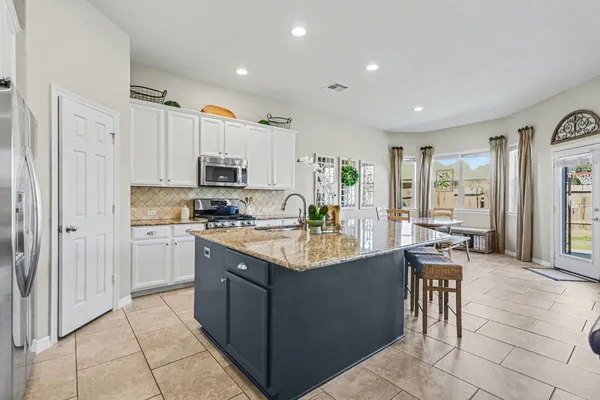 a kitchen with stainless steel appliances granite countertop a refrigerator oven a sink dishwasher and white cabinets with wooden floor