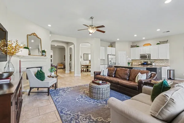 a living room with furniture kitchen view and a chandelier