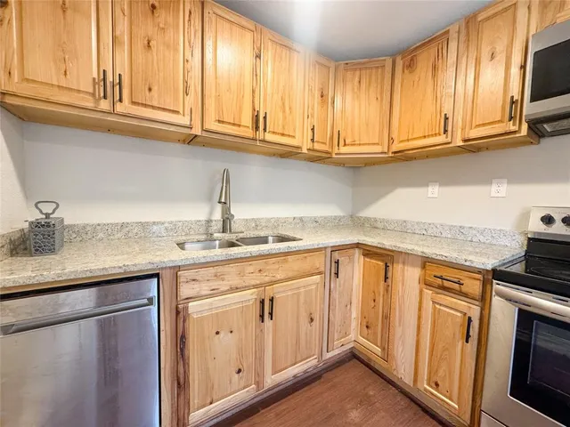 a kitchen with stainless steel appliances granite countertop a sink dishwasher stove and cabinets with wooden floor