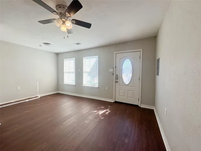 an empty room with wooden floor and windows