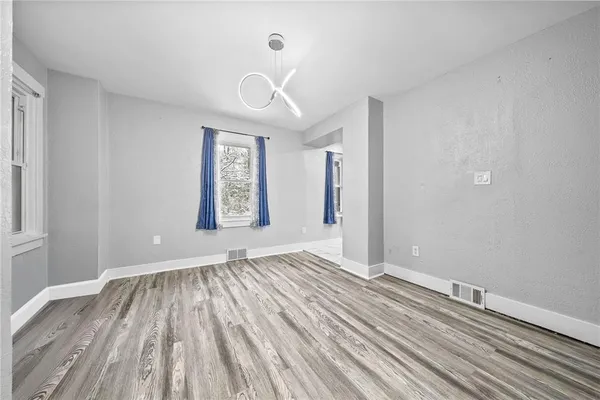 a view of an empty room with window and wooden floor