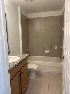 a bathroom with a granite countertop bathtub shower sink vanity and toilet