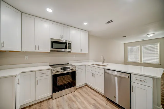 a kitchen with granite countertop white cabinets and black stainless steel appliances