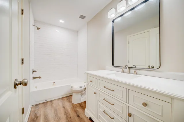 a bathroom with a granite countertop sink a toilet and a bathtub