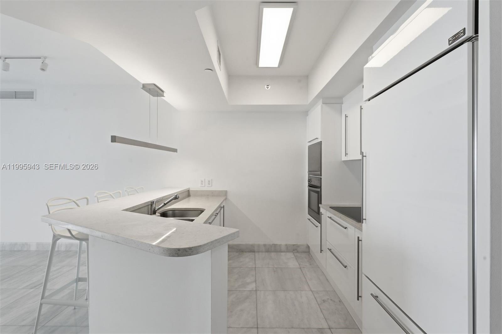 450 Alton Road, Unit 910 Miami Beach, FL 33139 - Photo 7 of 59 a kitchen that has a sink and a refrigerator