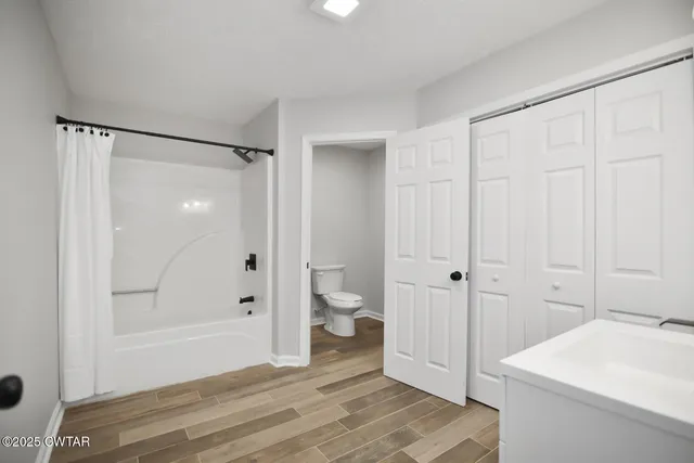 a bathroom with a granite countertop sink a toilet and shower