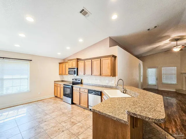 a large kitchen with stainless steel appliances granite countertop a stove a sink dishwasher a microwave oven and a refrigerator