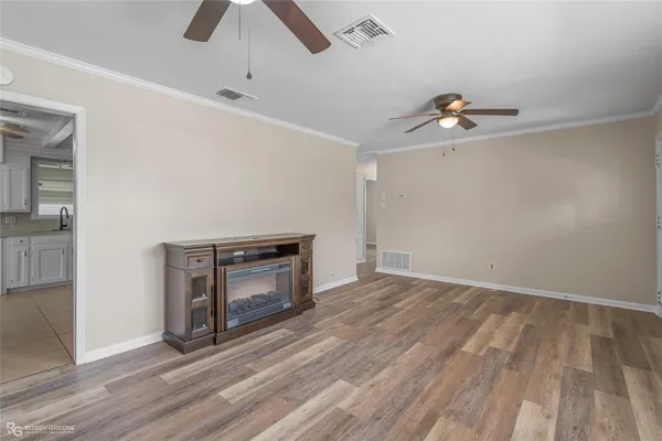 a view of an empty room with window and chandelier fan