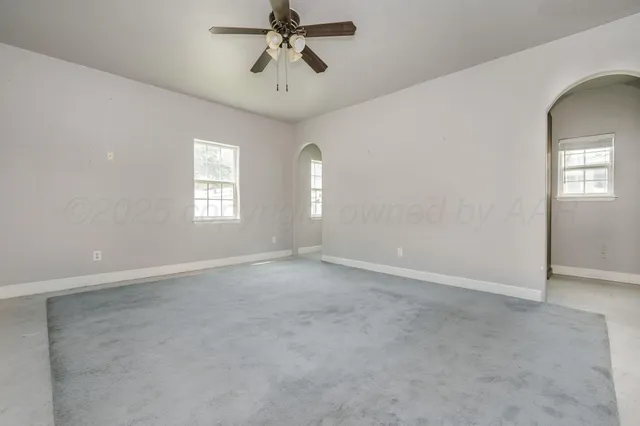 an empty room with windows and fan