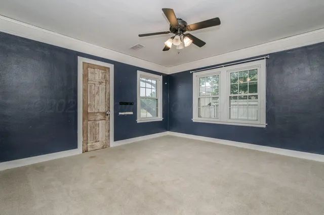 an empty room with windows and ceiling fan