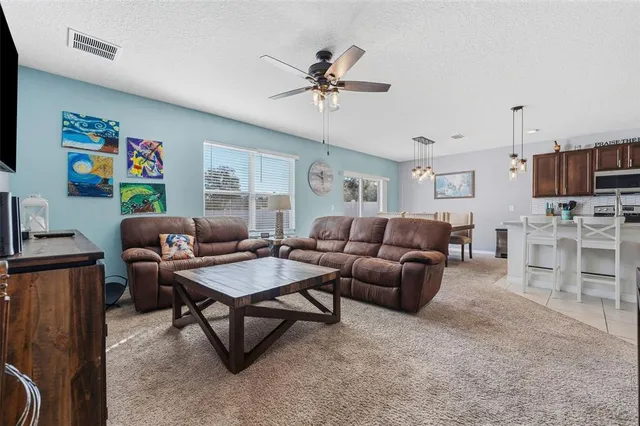 a kitchen with stainless steel appliances granite countertop a refrigerator a stove a sink a microwave and a dining table with wooden floor