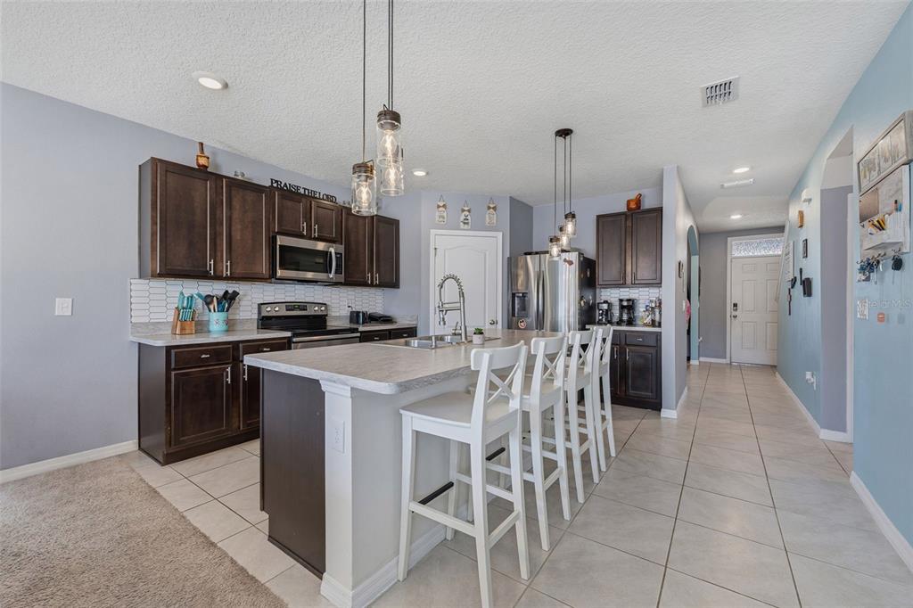 1526 White Hawk Way Groveland, FL 34736 - Photo 14 of 40 a kitchen with stainless steel appliances granite countertop a refrigerator a stove a sink a microwave and a dining table with wooden floor