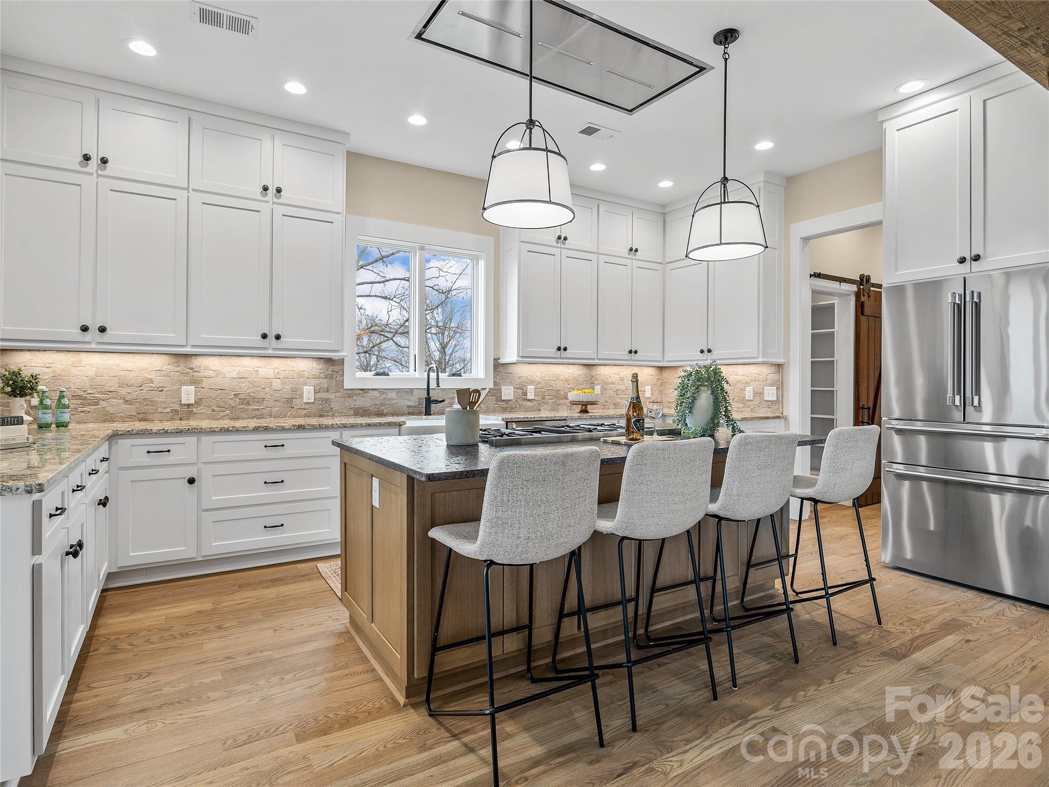 297 Mountain Meadows Lane, Unit 7 Tryon, NC 28782 - Photo 11 of 47 a kitchen with kitchen island granite countertop a table chairs refrigerator and microwave