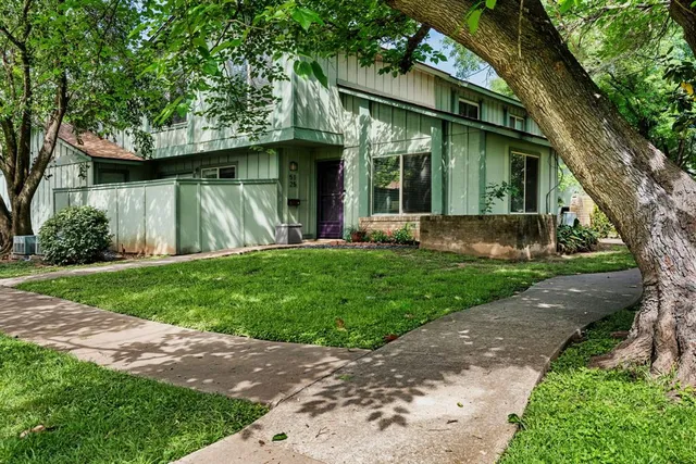 a view of a house with a yard and large tree