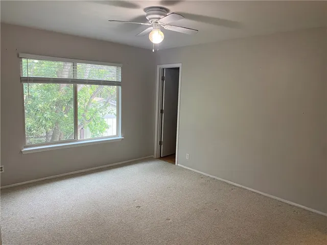 an empty room with a window and a fan