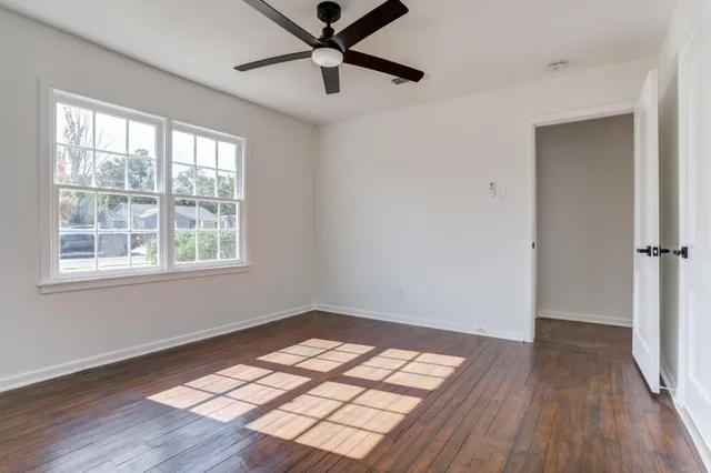a view of empty room with wooden floor and fan