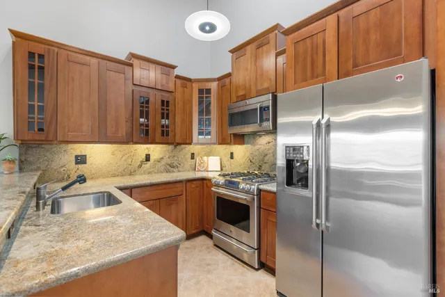 a kitchen with stainless steel appliances granite countertop a sink refrigerator and cabinets