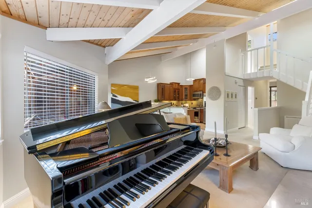 a living room with furniture a piano and a bookshelf
