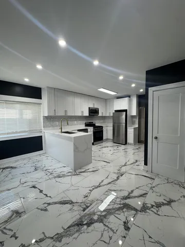 a kitchen with stainless steel appliances kitchen island granite countertop a refrigerator and a stove top oven