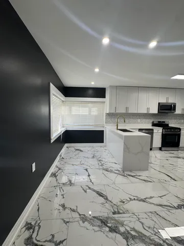 a kitchen with stainless steel appliances kitchen island granite countertop a sink and a stove