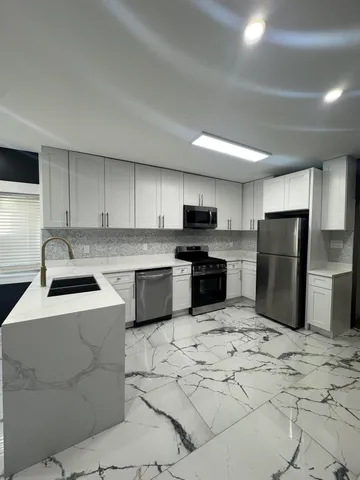 a kitchen with stainless steel appliances granite countertop a sink a stove a refrigerator and cabinets