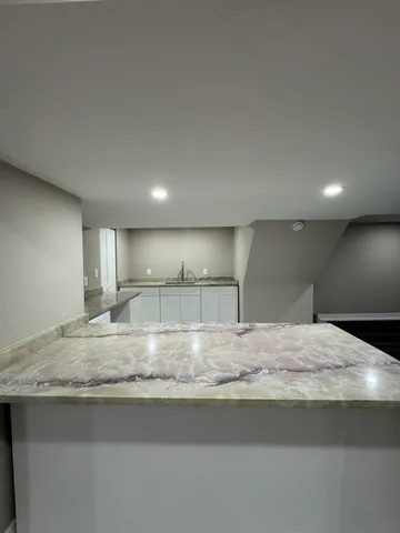 a kitchen with kitchen island granite countertop a sink and a stove