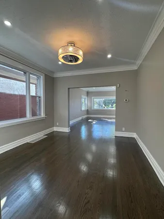 a view of an empty room with wooden floor and windows