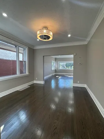 a view of an empty room with wooden floor and windows