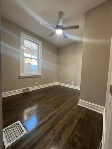 an empty room with wooden floor cabinet and windows