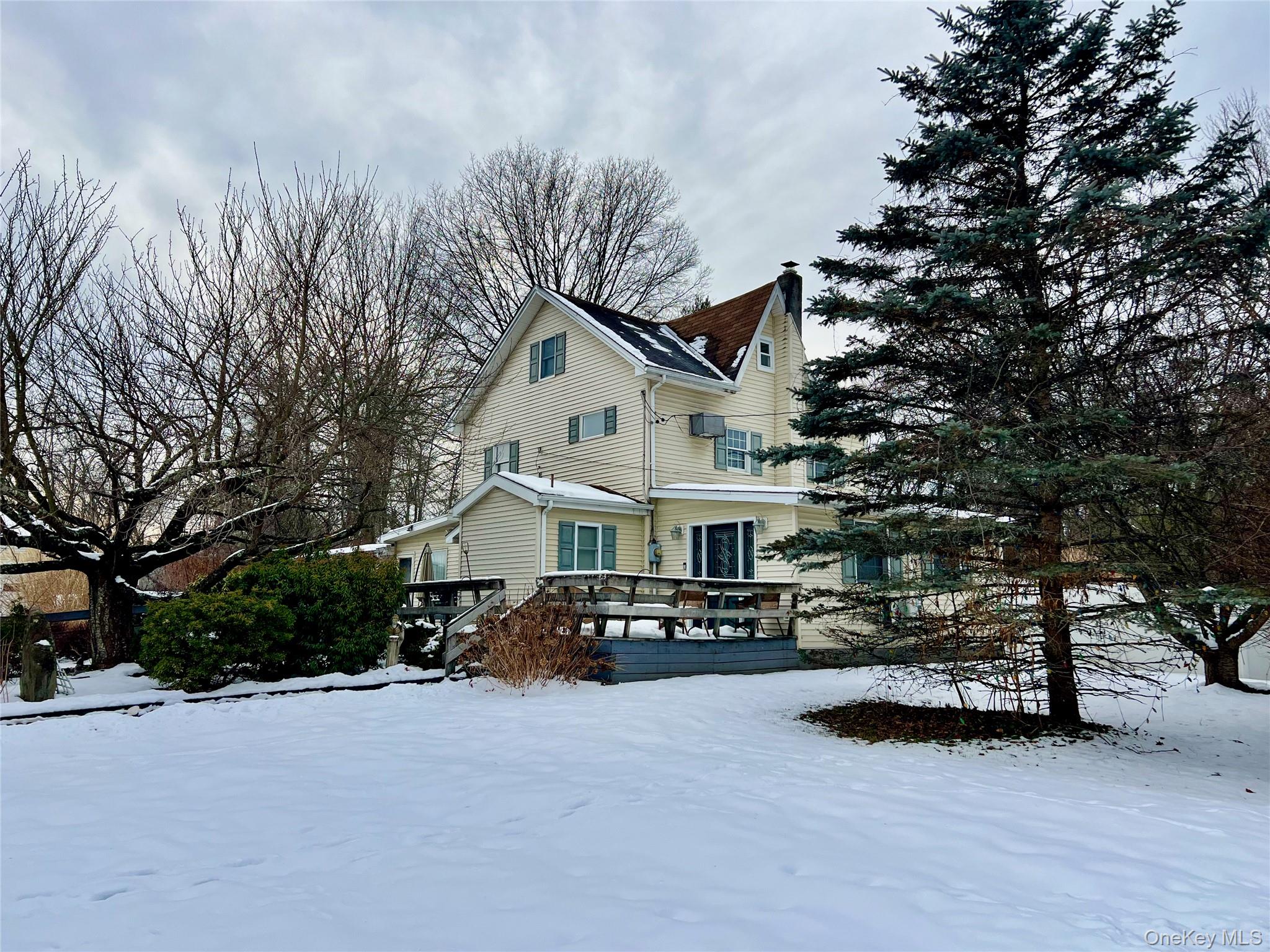 Snow covered property featuring a wooden deck and a chimney
