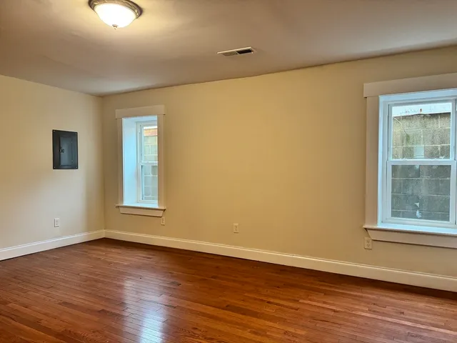 a view of an empty room with wooden floor and a window