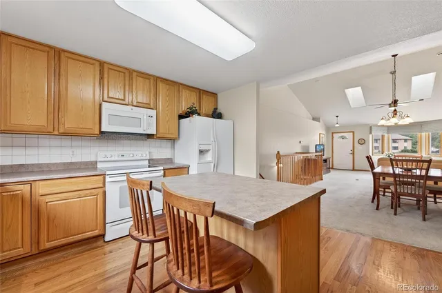 a kitchen with stainless steel appliances granite countertop table chairs and wooden cabinets