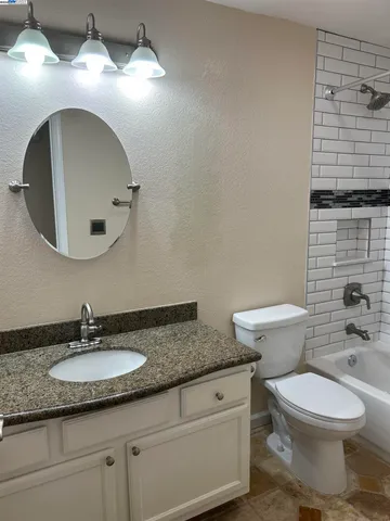 a bathroom with a granite countertop toilet a sink and a mirror