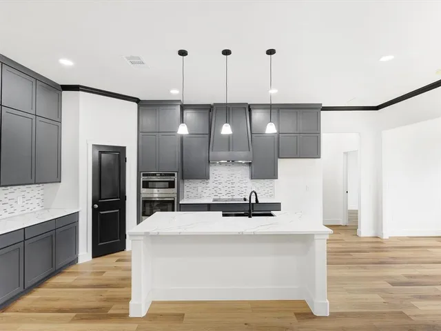 a view of a kitchen with kitchen island a counter top space stainless steel appliances and wooden floor
