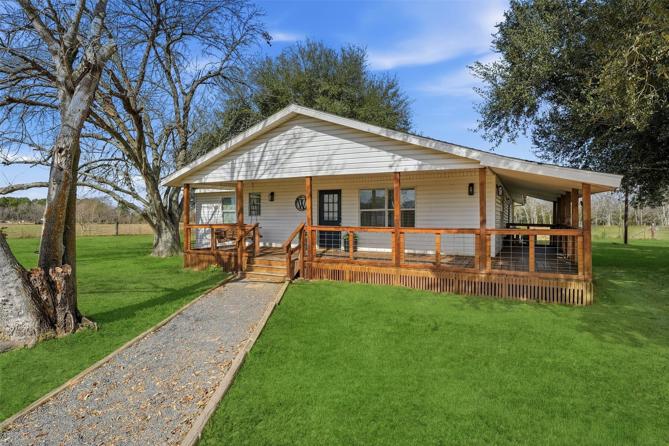 611 Reidland Road Crosby, TX 77532 - Photo 3 of 35 Charming single-story home with a spacious, covered porch, surrounded by lush greenery. Features a welcoming front path and mature trees, perfect for enjoying outdoor living in a serene setting.
