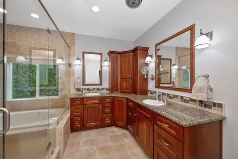 a bathroom with a granite countertop tub sink shower and mirror