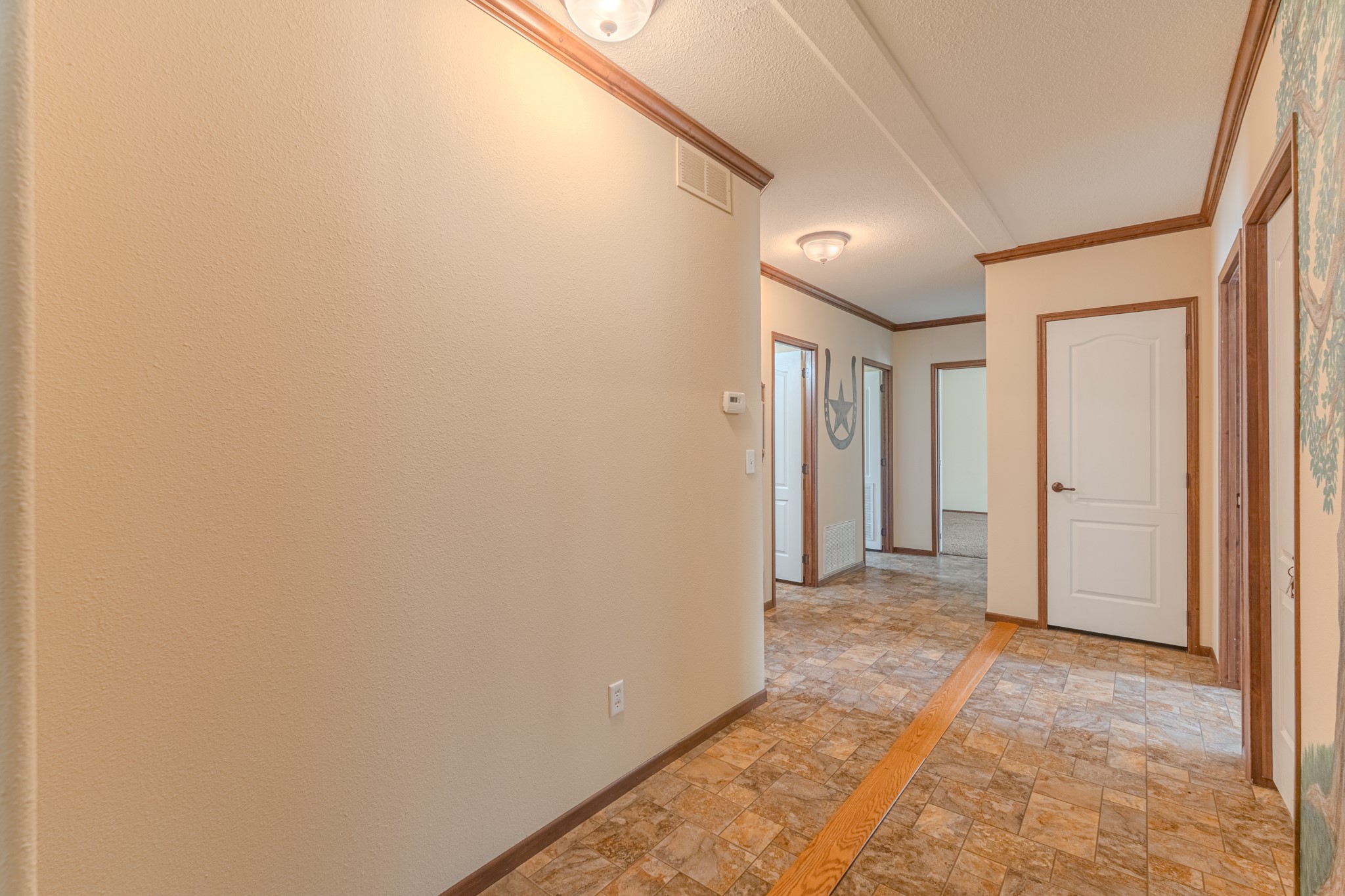 115 Canadian Drive Trinity, TX 75862 - Photo 15 of 41 Bright and spacious hallway with neutral wall colors, and wood trim. It leads to multiple rooms, featuring stylish lighting fixtures and a clean, welcoming atmosphere.