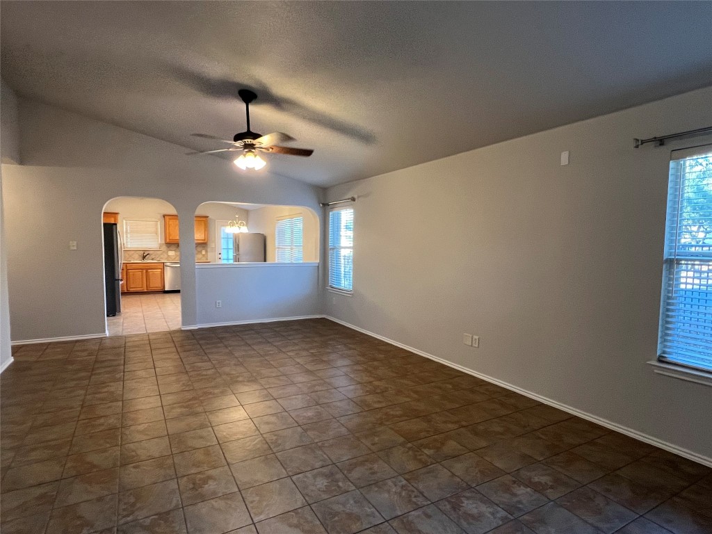 an empty room with windows and chandelier fan