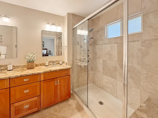a bathroom with a granite countertop sink a mirror a glass door a shower and vanity