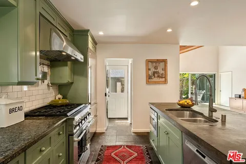a kitchen with stainless steel appliances granite countertop a sink a stove a dining table and chairs