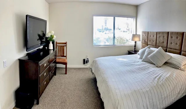 a bedroom with a bed and a flat tv screen on dresser