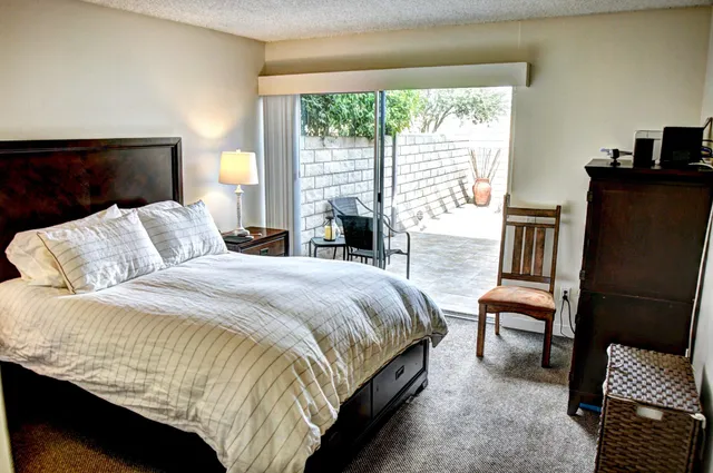 a bedroom with a bed wooden floor and a large window